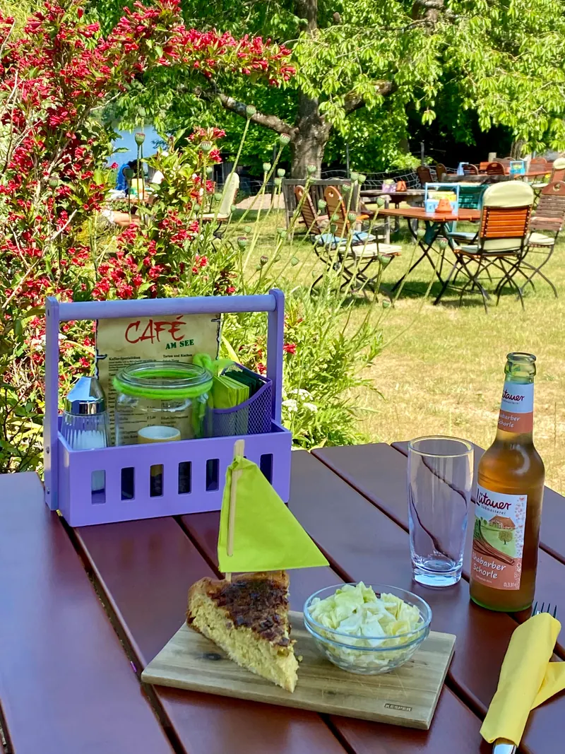 Quiche mit Salat und Rhabarberschorle auf einem Tisch im Garten des Café Brandtschatz